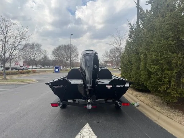 Slide: The Image of 2025 Tracker Pro Team 190 boat on trailer, parked in a lot with trees and cloudy sky. - 6