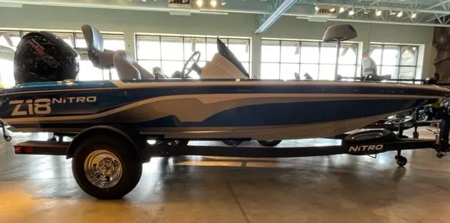 The Image of 2025 Nitro Z18 boat in showroom, blue and white design, on trailer. - 0