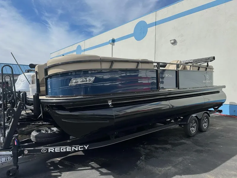 Slide: The Image of 2025 Regency 230 DL3 pontoon boat on trailer, parked outdoors. - 1