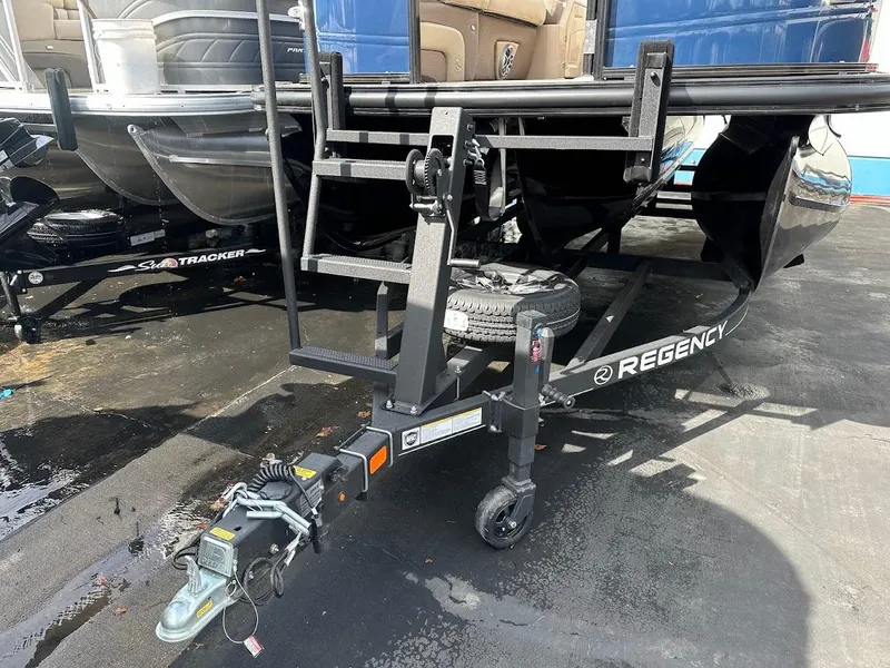 Slide: The Image of 2025 Regency 230 DL3 boat trailer hitch on wet pavement. - 3