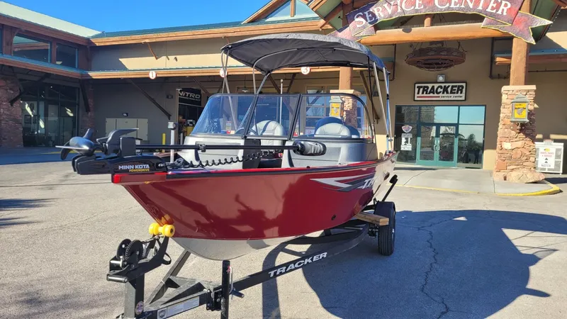 Slide: The Image of 2025 Tracker Pro Guide V-16 WT boat in red, parked outside a service center. - 3