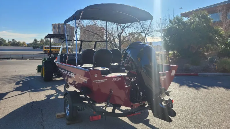 Slide: The Image of 2025 Tracker Pro Guide V-16 WT boat with canopy and outboard motor in a sunny parking lot. - 5