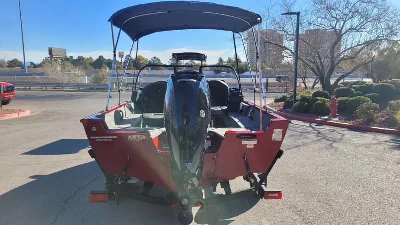 Slide: The Image of 2025 Tracker Pro Guide V-16 WT boat with canopy, parked outdoors. - 6