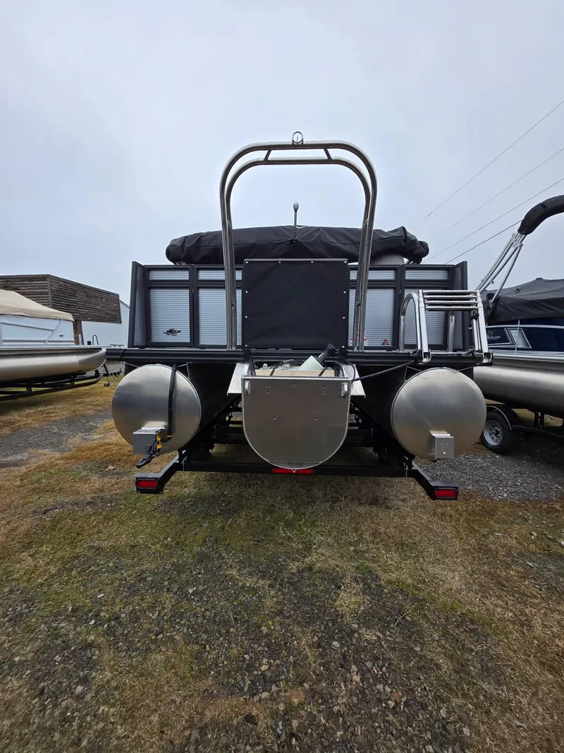 Slide: The Image of 2025 Qwest Splash Pad M-Class pontoon boat, rear view, parked on gravel. - 12