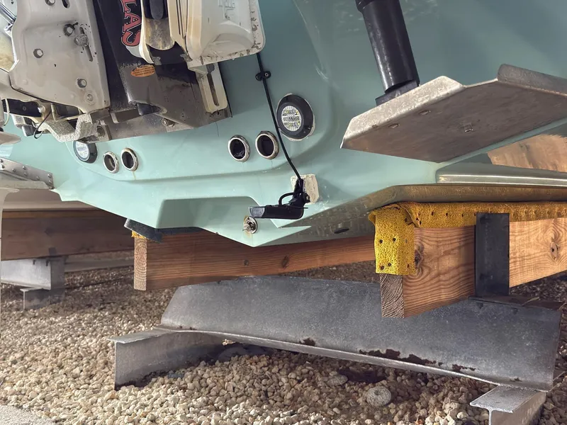 Slide: The Image of 2020 Tidewater 2300 Carolina Bay boat on wooden supports, showing hull and engine details. - 19