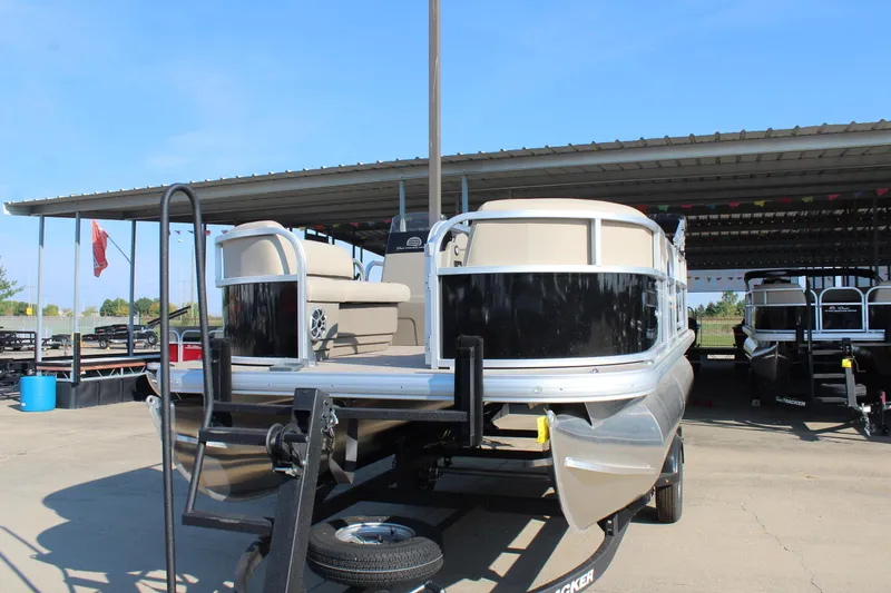 Slide: The Image of 2025 Sun Tracker Party Barge 16 DLX pontoon boat on trailer under a metal canopy. - 2