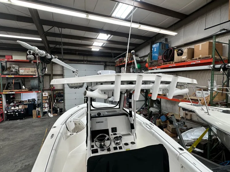 Slide: The Image of 2020 Sea Pro 259 Center Console boat in a workshop, showcasing its helm and equipment. - 2