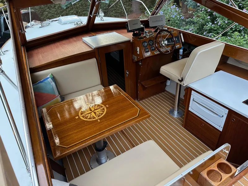 Slide: The Image of 1973 Chris-Craft Sport Deck interior with wooden table, seating, and steering area. - 11