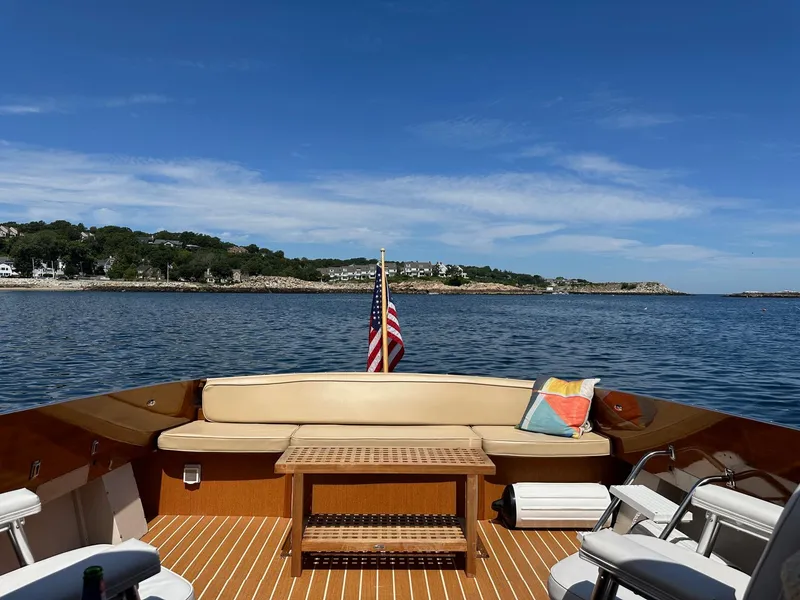 Slide: The Image of 1973 Chris-Craft Sport Deck boat with seating, table, and American flag on a sunny day. - 14