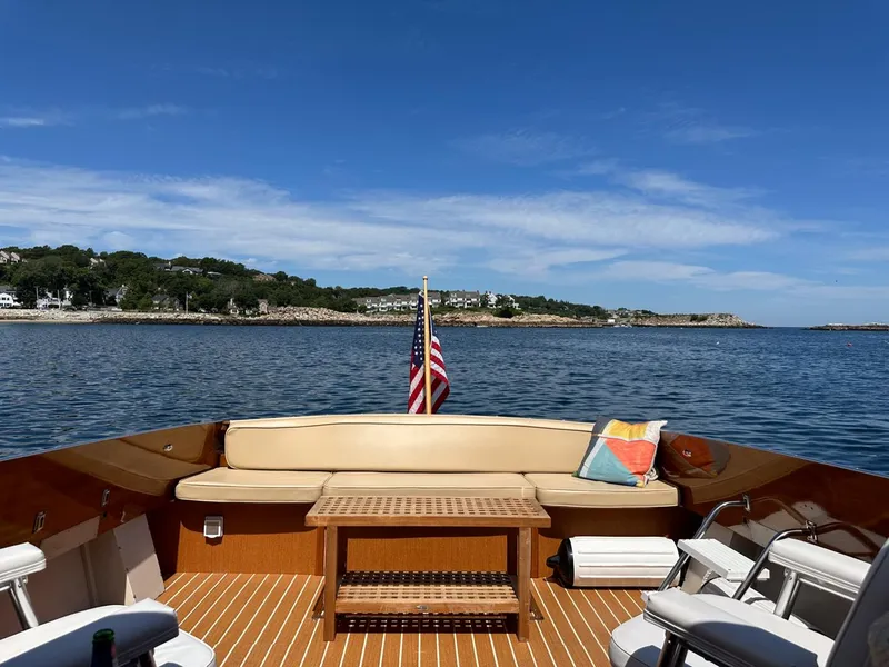 Slide: The Image of 1973 Chris-Craft Sport Deck boat with seating, table, and American flag on a sunny day. - 15