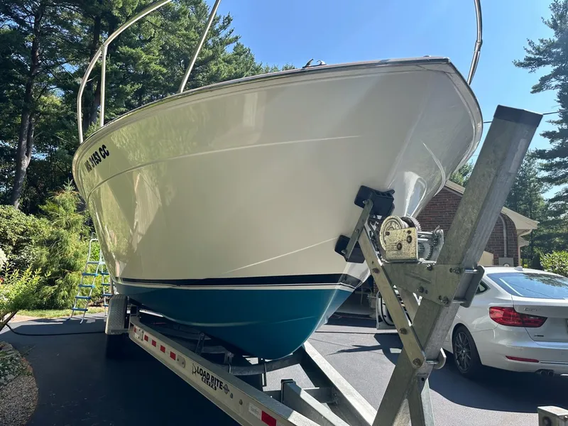 Slide: The Image of 1973 Chris-Craft Sport Deck boat on trailer, parked in driveway with trees in background. - 4