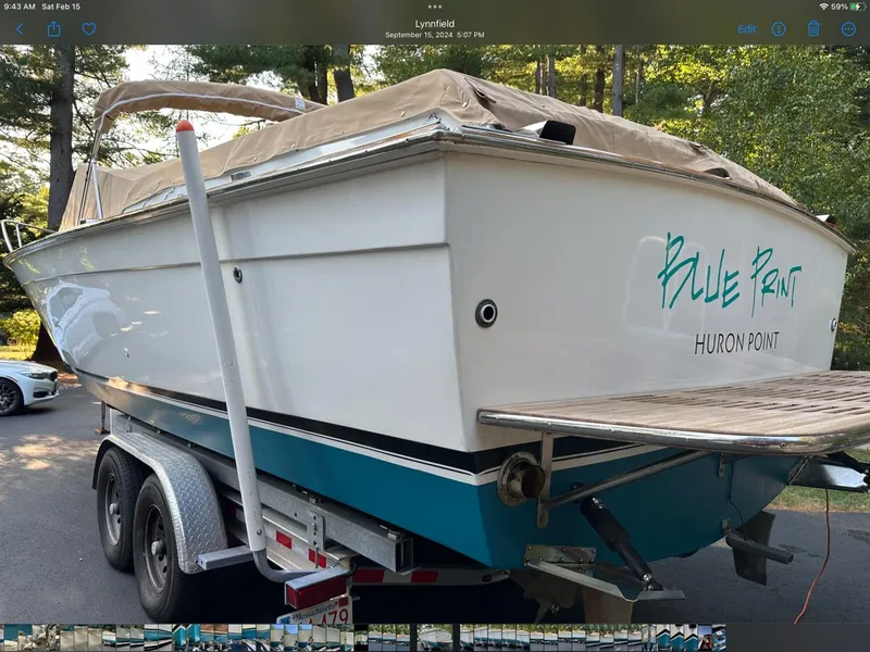 Slide: The Image of 1973 Chris-Craft Sport Deck boat on trailer, named "Blue Print," parked outdoors. - 6
