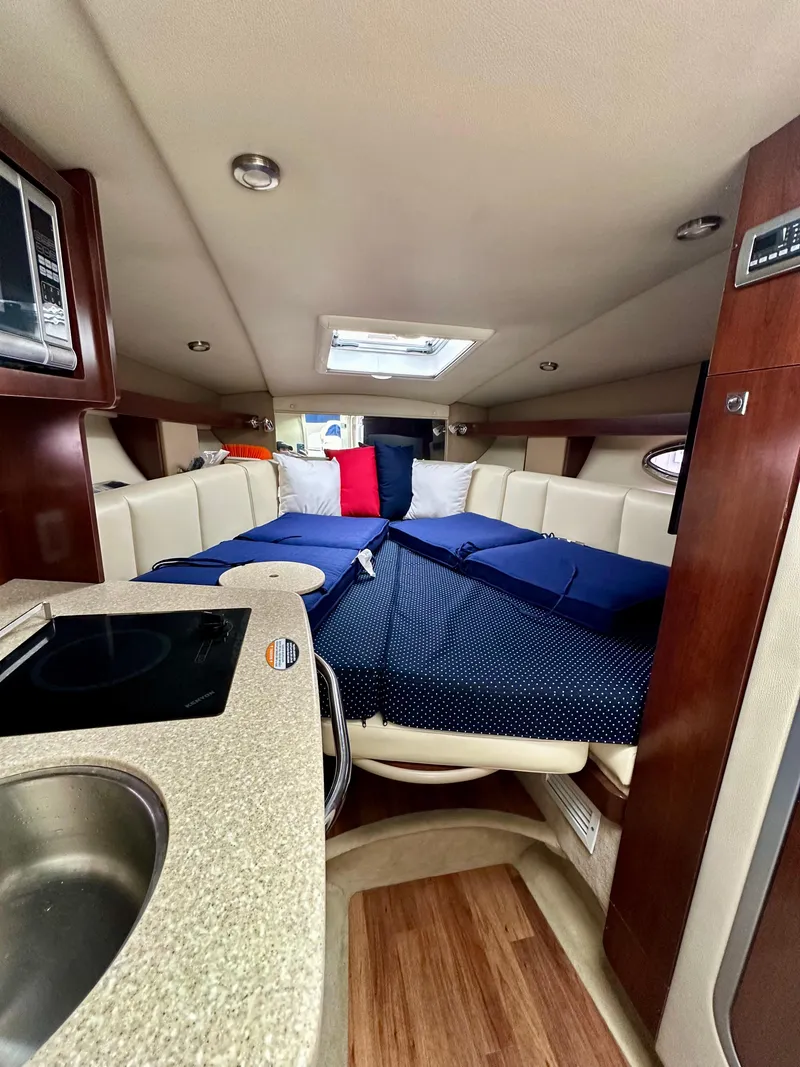Slide: The Image of 2014 Chaparral 270 Signature cabin interior with bed, kitchenette, and wood flooring. - 14