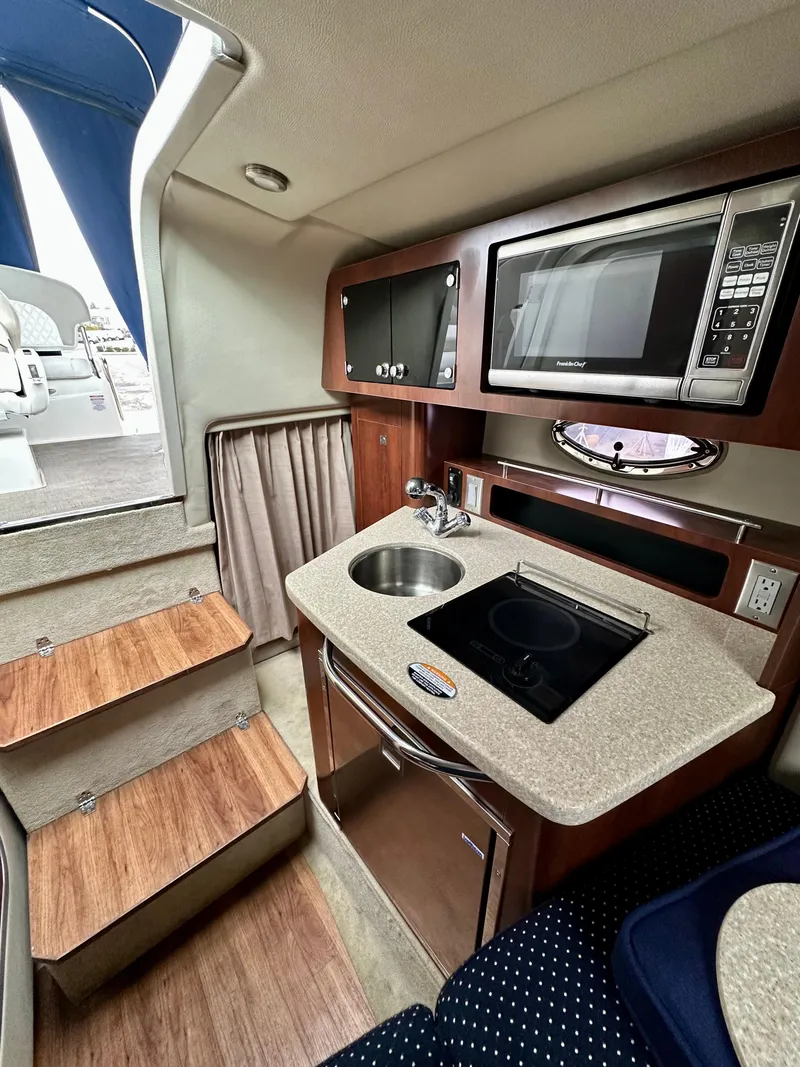 Slide: The Image of 2014 Chaparral 270 Signature boat interior with kitchenette, microwave, and stairs. - 16