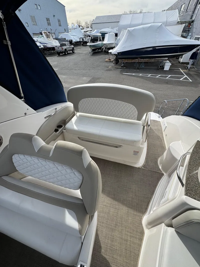 Slide: The Image of 2014 Chaparral 270 Signature boat interior with white seating, docked in a marina. - 21