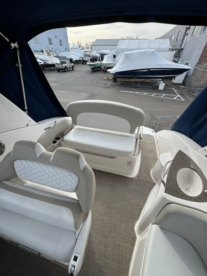 Slide: The Image of 2014 Chaparral 270 Signature boat interior with beige seating and covered docked boats in the background. - 26