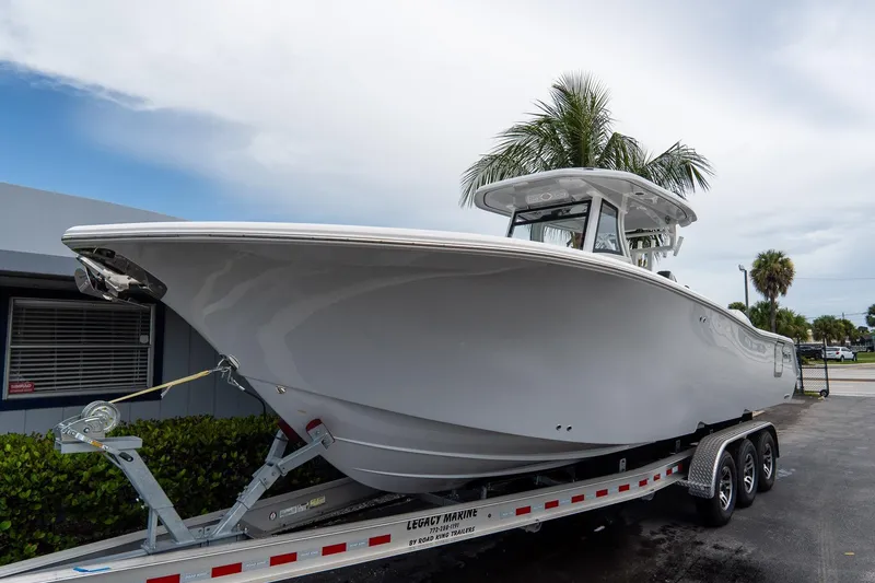Slide: The Image of 2025 Tidewater 302CC Adventure boat on trailer, parked outdoors under cloudy sky. - 11