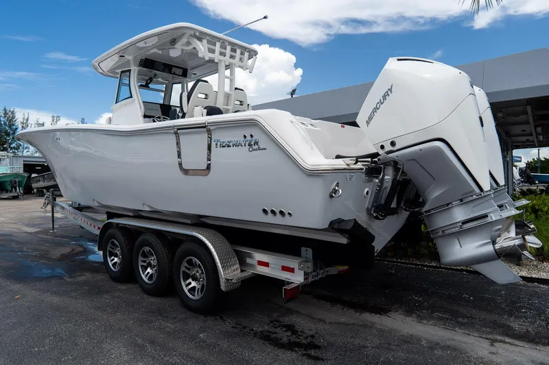 Slide: The Image of 2025 Tidewater 302CC Adventure boat on trailer with Mercury engine, parked outdoors. - 13