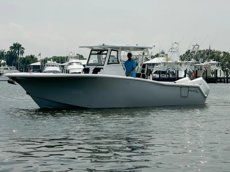 Slide: The Image of 2025 Tidewater 302CC Adventure boat on calm water near a marina. - 3