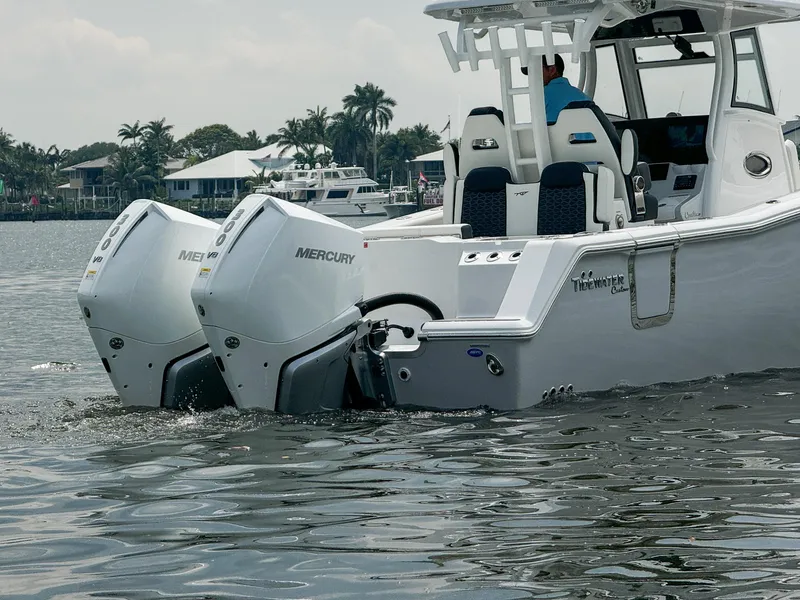 Slide: The Image of 2025 Tidewater 302CC Adventure boat with dual Mercury engines on calm water. - 4