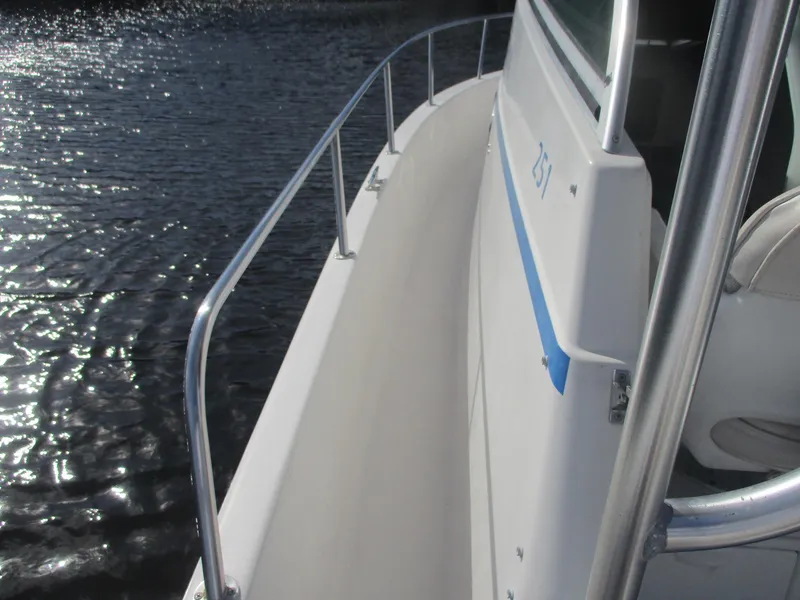 Slide: The Image of 1997 Pro-Line 251 WA boat side view on water, showcasing railing and cabin details. - 27