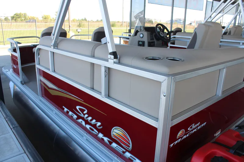 Slide: The Image of 2025 Sun Tracker Bass Buggy 16 XL Select pontoon boat, red exterior, beige seating. - 2