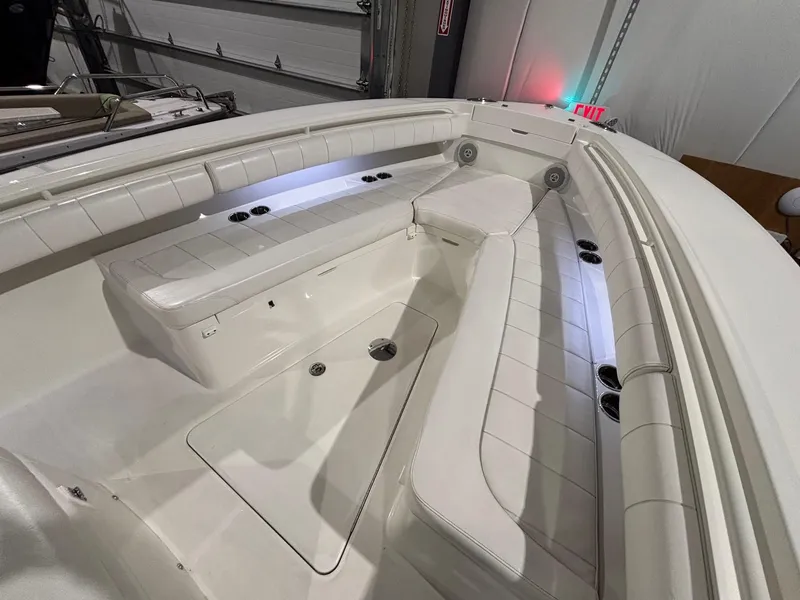 Slide: The Image of 2015 Regulator 25 boat interior with white cushioned seating and storage compartments. - 18