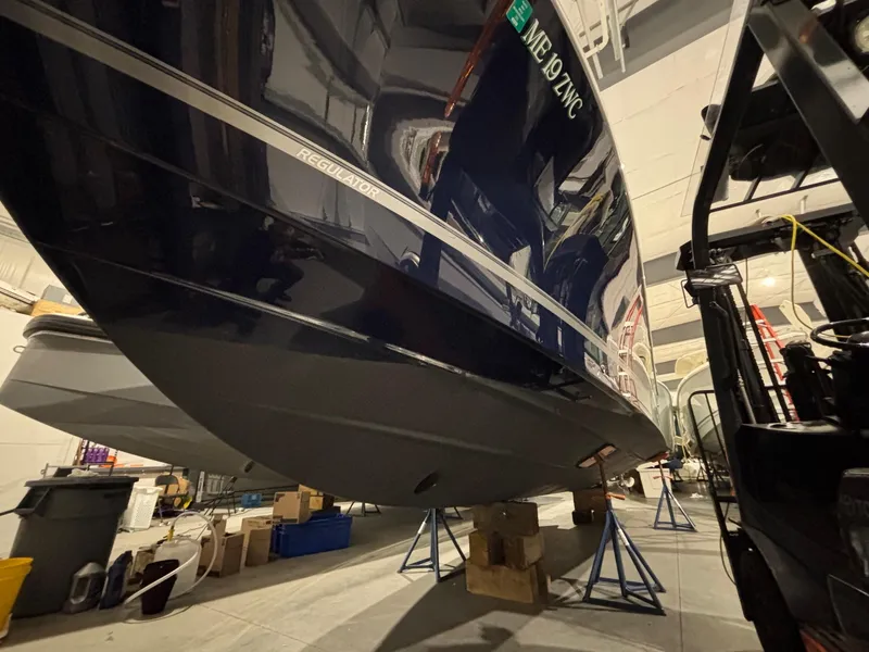 Slide: The Image of 2015 Regulator 25 boat in storage, elevated on stands, indoor setting. - 2