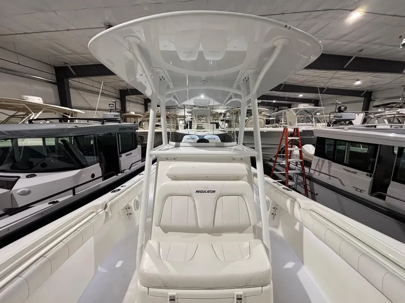 Slide: The Image of 2015 Regulator 25 boat interior with seating and T-top in a showroom. - 20