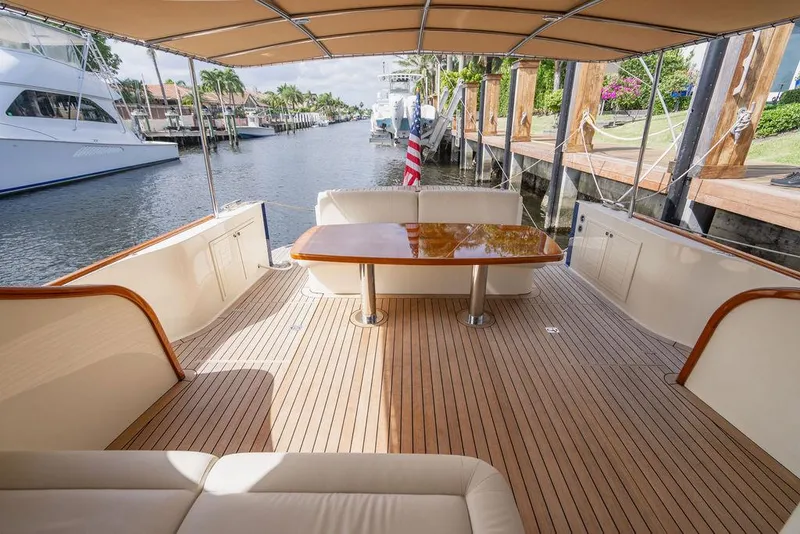 Slide: The Image of 2015 Palm Beach Motor Yachts PB52 deck with seating and table, docked by a canal. - 16