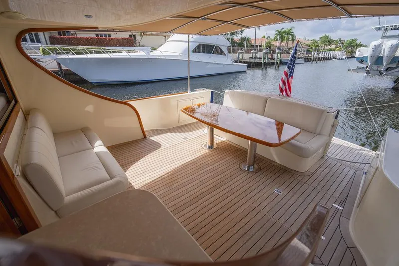 Slide: The Image of 2015 Palm Beach Motor Yachts PB52, elegant deck with seating and table, docked by waterfront. - 17
