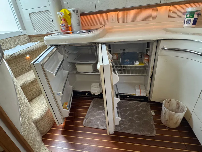 Slide: The Image of Interior of 1995 Sea Ray 450 Sundancer with open fridge and cleaning supplies. - 22