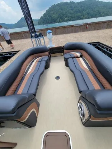 Slide: The Image of 2025 Aloha 30' Paradise Sundeck with luxurious seating, docked by a scenic lake. - 16