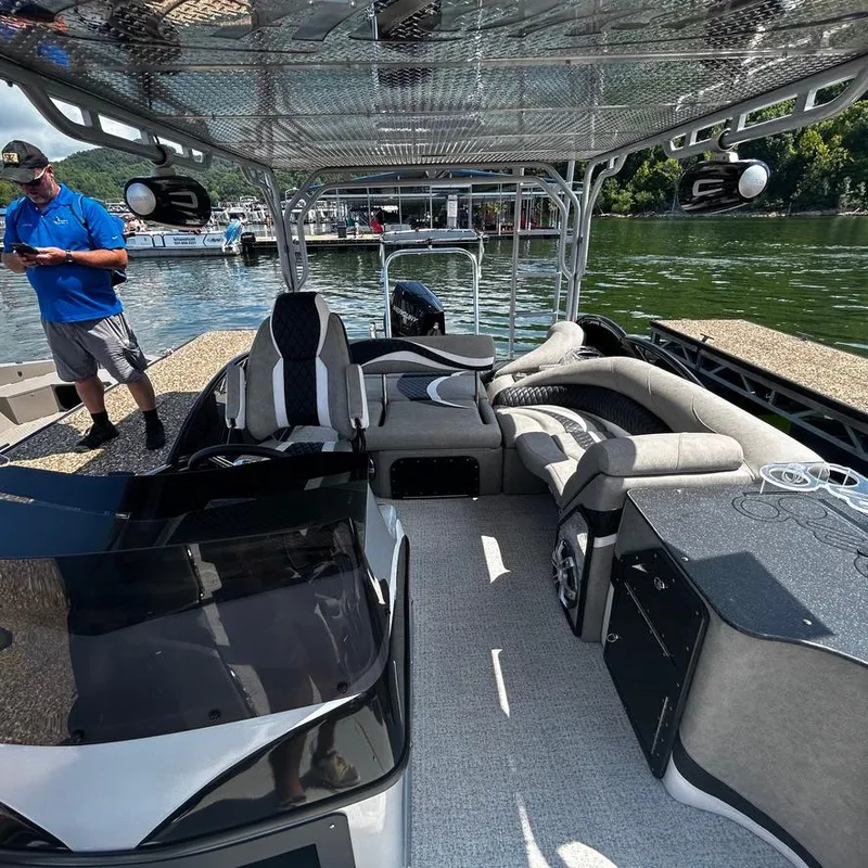 Slide: The Image of 2025 Aloha 30' Paradise Sundeck boat interior with seating and helm, docked by the water. - 5