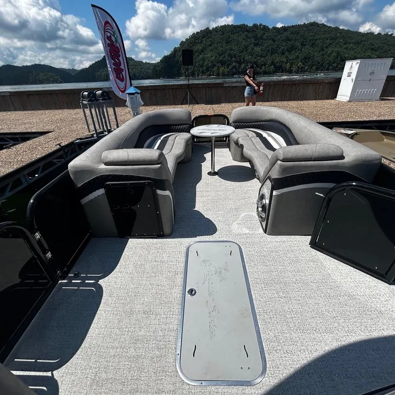 Slide: The Image of 2025 Aloha 30' Paradise Sundeck with spacious seating, set against a scenic lake backdrop. - 9