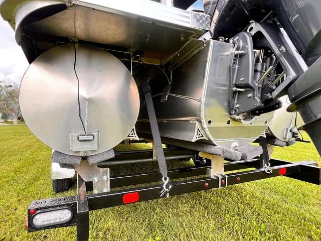 Slide: The Image of Aloha 2025 23' Paradise Arch Sport Tower boat underside on trailer, showcasing pontoons and motor. - 19