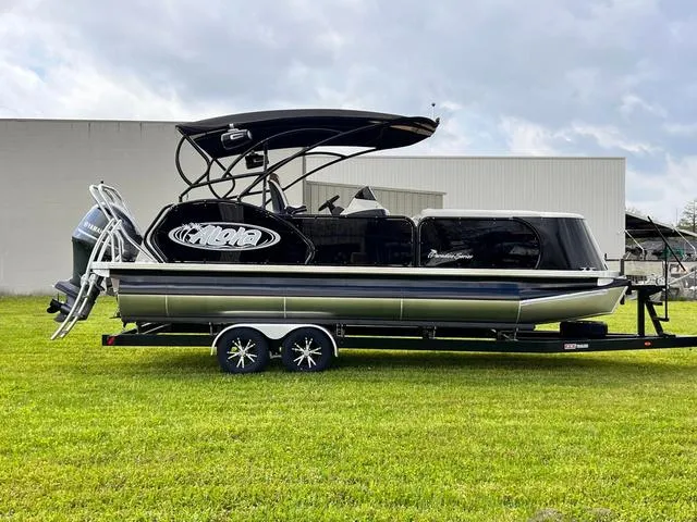 Slide: The Image of 2025 Aloha 23' Paradise Arch Sport Tower boat on trailer, parked on grass. - 2