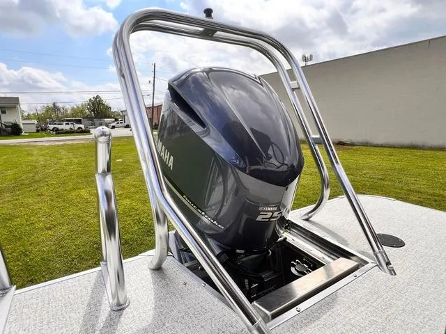 Slide: The Image of 2025 Aloha 23' Paradise Arch Sport Tower with Yamaha outboard motor, parked on grass. - 25