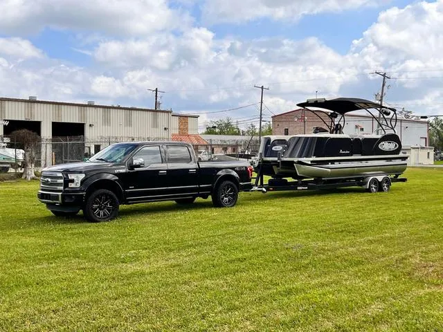 Slide: The Image of A black truck towing a 2025 Aloha 23' Paradise Arch Sport Tower boat on grass. - 5