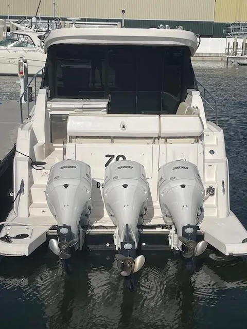 Slide: The Image of 2021 Regal 38 XO boat with triple outboard engines docked at a marina. - 10