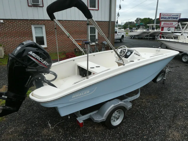 Slide: The Image of 2025 Boston Whaler 130 Super Sport boat on trailer, featuring a Mercury outboard motor. - 2
