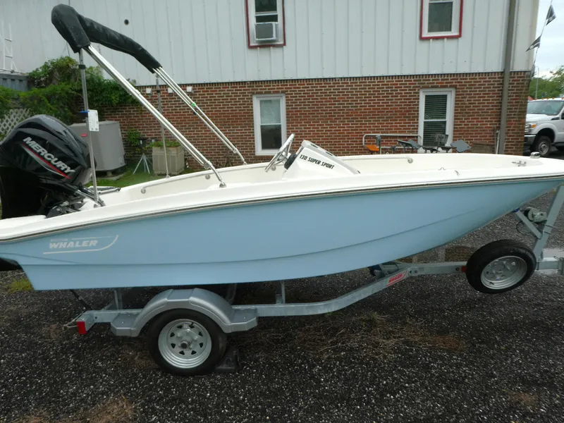Slide: The Image of 2025 Boston Whaler 130 Super Sport boat on trailer, parked outdoors. - 3