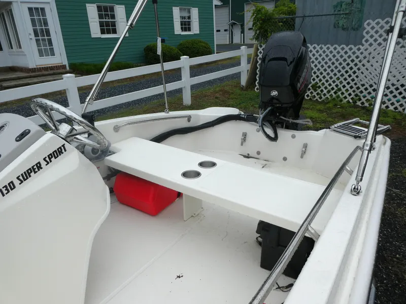 Slide: The Image of 2025 Boston Whaler 130 Super Sport boat interior with steering wheel and outboard motor. - 5