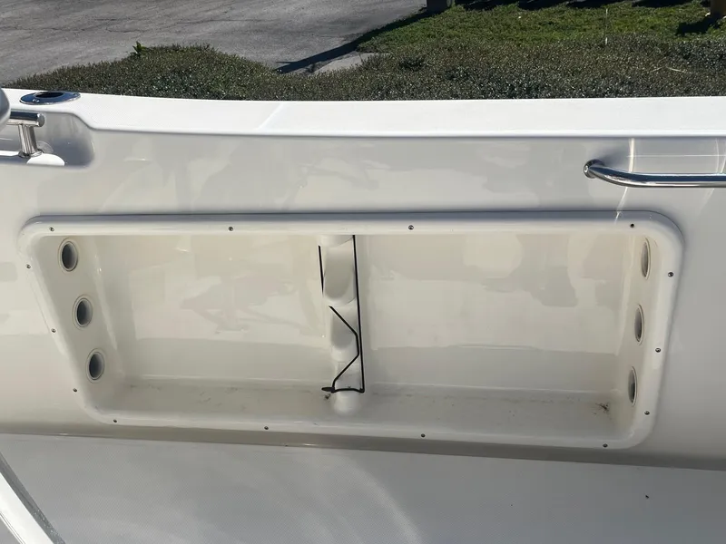 Slide: The Image of 2022 Bulls Bay 230 Center Console boat storage compartment, white interior, outdoor setting. - 9