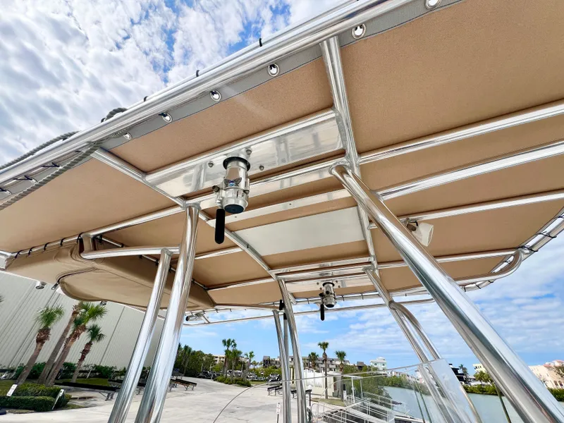 Slide: The Image of 2019 Parker 2300 Center Console boat with beige canopy and metal frame, docked near palm trees. - 16