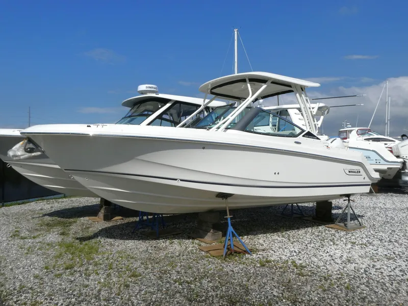 Slide: The Image of 2025 Boston Whaler 240 Vantage boat on display, side view, on gravel surface. - 1
