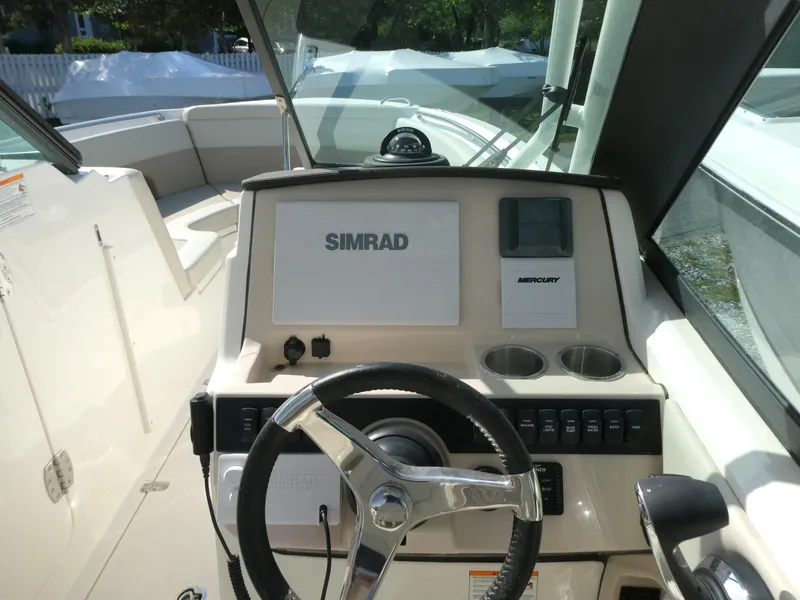 Slide: The Image of 2025 Boston Whaler 240 Vantage boat dashboard with Simrad display and steering wheel. - 11