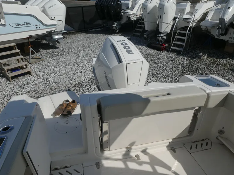 Slide: The Image of 2025 Boston Whaler 240 Vantage boat with powerful outboard engine in a gravel lot. - 4