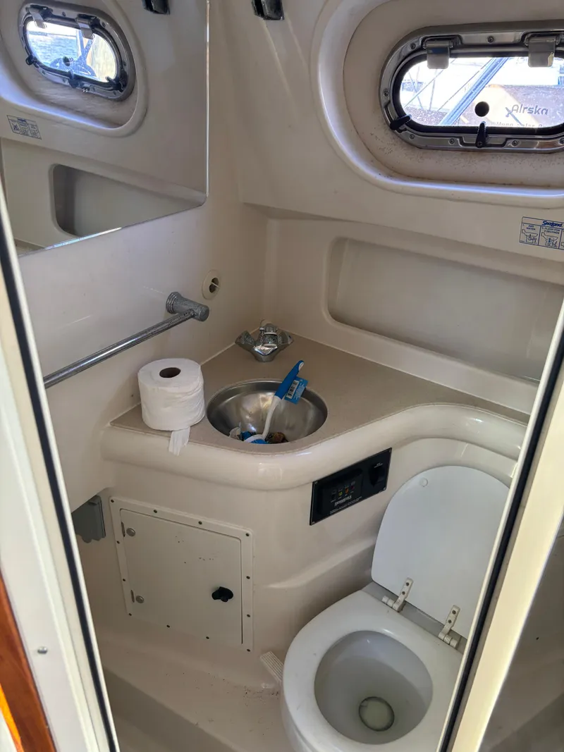 Slide: The Image of 2006 Pursuit 3370 Offshore boat bathroom with sink, toilet, and porthole windows. - 11