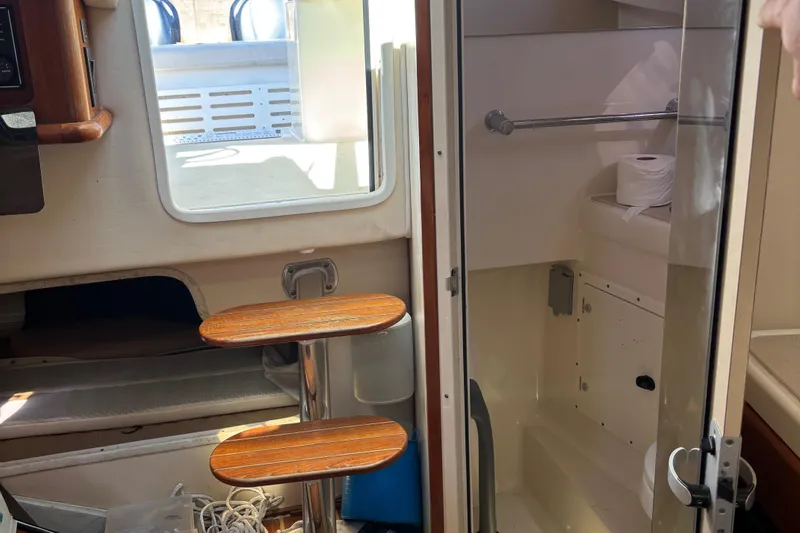 Slide: The Image of Interior of a 2006 Pursuit 3370 Offshore boat, featuring a compact bathroom and wooden steps. - 17